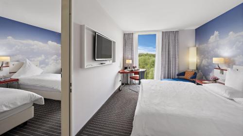a hotel room with two beds and a flat screen tv at Hey Lou Hotel Friedrichshafen in Friedrichshafen
