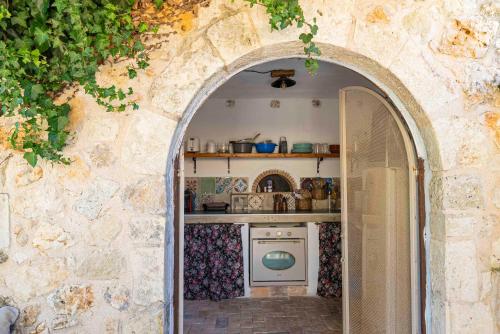 une arche menant à une cuisine dans un mur de pierre dans l'établissement Zois & Mavretta House, à Kariá