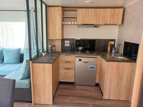 une cuisine avec des placards en bois et un canapé bleu dans l'établissement cambing la carabasse, à Vias