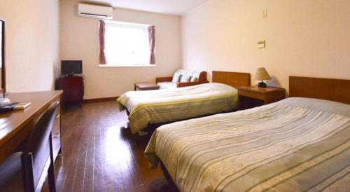 a hotel room with two beds and a desk at Petit Hotel Key West Club in Naha