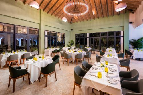 a dining room with white tables and chairs and windows at Viva Miches by Wyndham, a Trademark All Inclusive Resort in Miches