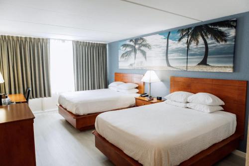 a hotel room with two beds and a painting on the wall at enVision Hotel Miami International Airport in Miami