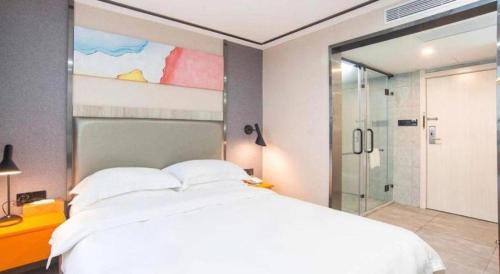 a bedroom with a large white bed and a shower at 7 Days Premium Zhuhai Gongbei Light Railway Branch in Zhuhai