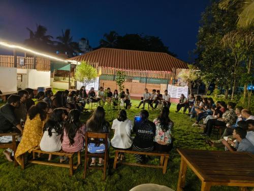 a group of people sitting on chairs in the grass at The Palmyrah Tenements in Mysore