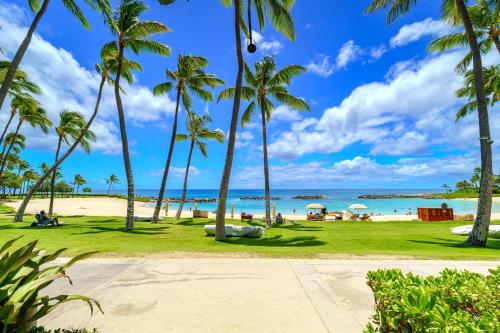 a beach with palm trees and the ocean at KBM Resorts FREE CAR Beach Villas at Ko Olina BVK-B-308 Beachfront Villa in Kapolei