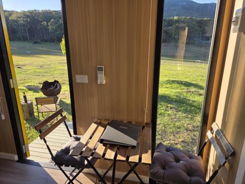 eine Veranda mit Tisch und Stühlen und einem Laptop in der Unterkunft Paddock & Peak by Tiny Away 