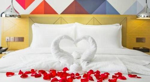 two swans making a heart on a bed with red roses at Borrman Hotel Zhuhai Gongbei Port Fuhuali Light Rail in Zhuhai
