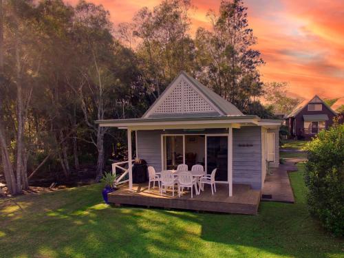 a house with a deck with chairs and a table at Beach Shack on the Lagoon in Berrara