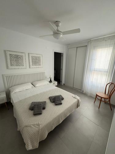 a white bedroom with a bed and a ceiling fan at Almar Relax in Daimuz