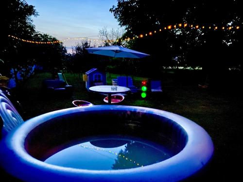 a tub in a yard with a table and an umbrella at Kuća za odmor Bećarsko Utočište in Vinkovci