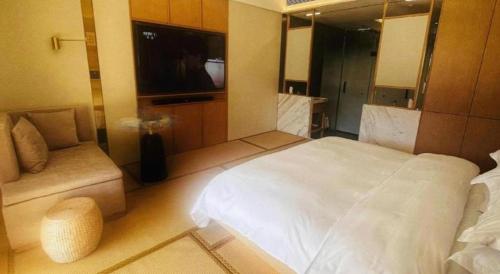 a bedroom with a large white bed and a television at Kunming Dianchi Garden Hotel & Spa in Kunming