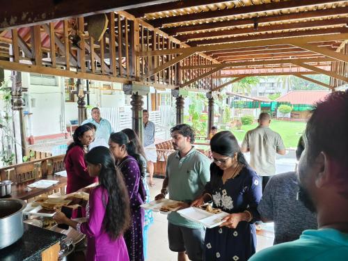 a group of people standing in a kitchen with food at The Palmyrah Tenements in Mysore