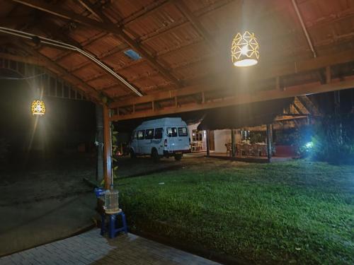 a garage with a white van parked under a roof at night at Raagabynature home stay in Gendehalli