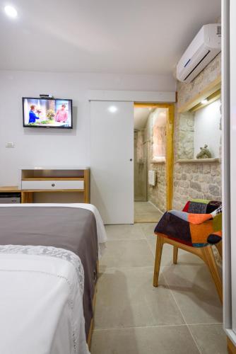 a bedroom with a bed and a tv on the wall at Villa Kudelik - Stone Story in Trogir