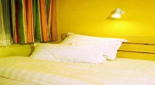 a bed with white pillows and a yellow wall at 7 Days Inn Changzhou Yancheng Technology Metro Station in Changzhou
