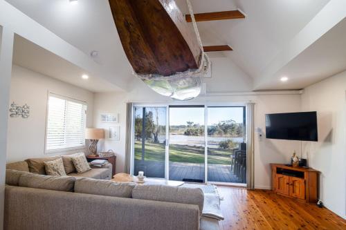 a living room with a couch and a large window at Beach Shack on the Lagoon in Berrara
