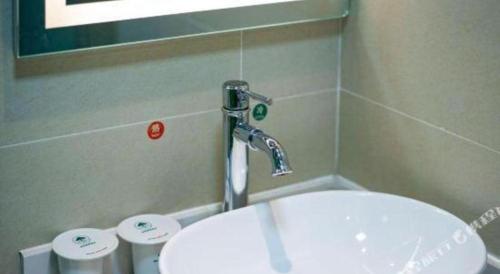 a bathroom with a sink and a faucet at GreenTree Inn Huayin Huashan Town Huashan Scenicspot Express Hotel in Huayin
