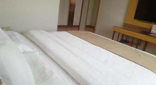 a white bed in a room with a television at GreenTree Inn Huayin Huashan Town Huashan Scenicspot Express Hotel in Huayin