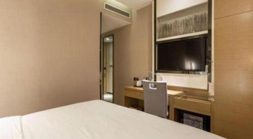 a bedroom with a bed and a desk and a television at Lavande Hotels Suzhou Railway Station in Suzhou