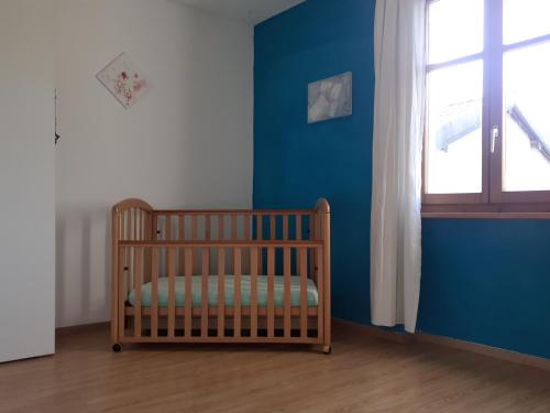 a crib in a room with a blue wall at Casa Eva - OsoleMio in Monteggio