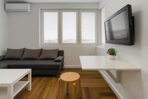 a living room with a couch and a tv on a wall at North Panoramic Apartment in the art district of Kapana in Plovdiv