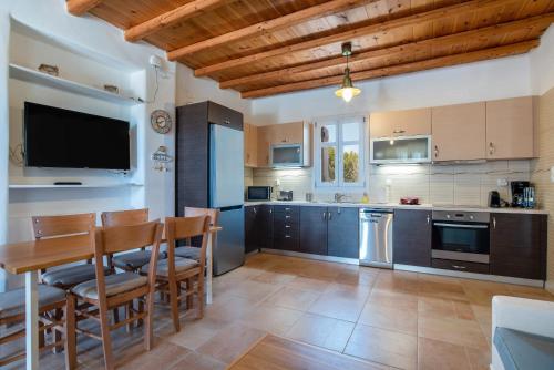 a kitchen with a table and chairs and a television at Blue Xenia Villas Paros in Chrissi Akti