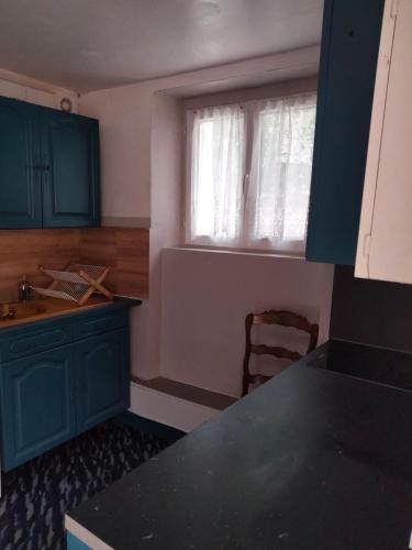 une cuisine avec des placards bleus et une fenêtre dans l'établissement Appartement Cosy à Nemours Hameau Chaintreauville, à Saint-Pierre-lès-Nemours