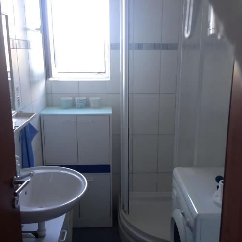 a white bathroom with a sink and a shower at Babe beach Apartment in Novalja