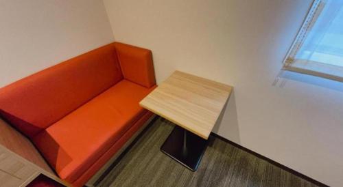 an orange couch with a wooden table in a room at KEIKYU EX INN Hamamatsucho Daimon-Station (Tokyo) in Tokyo