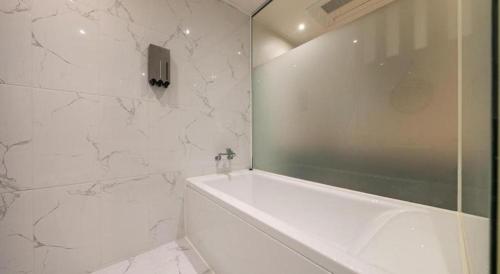 a white bathroom with a tub and a shower at Crossing Hotel in Seoul