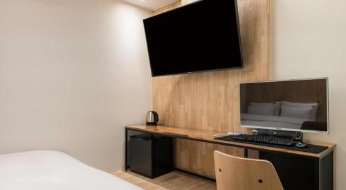 a hotel room with a tv and a bed and a desk at Crossing Hotel in Seoul