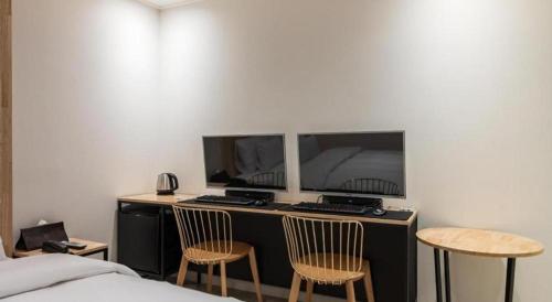 a bedroom with a desk with two monitors and two chairs at Crossing Hotel in Seoul