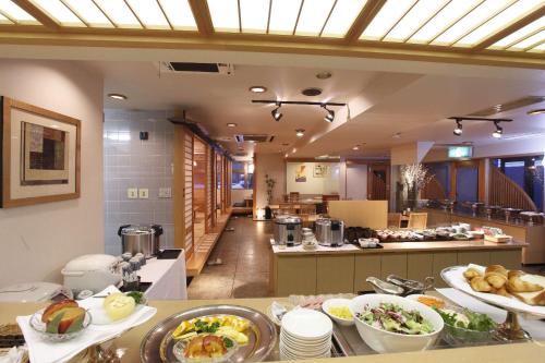 uma cozinha com muitos pratos de comida numa mesa em Hirosaki Plaza Hotel em Hirosaki