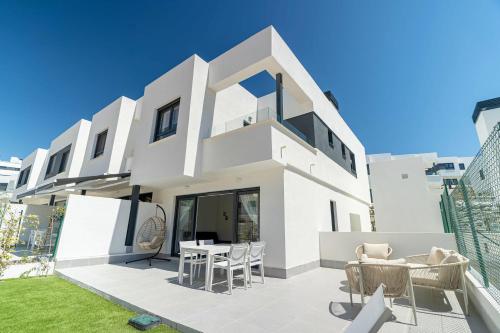 ein weißes Haus mit Stühlen und einem Tisch in der Unterkunft Serena Village beautiful 3 bedroom terraced house close to the beach in La Cala de Mijas