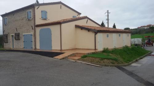 ein weißes Gebäude mit einer blauen Tür neben einer Straße in der Unterkunft Casa Monsignore in San Giovanni in Marignano