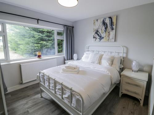 a white bedroom with a large bed and a window at Chillon in Evesham