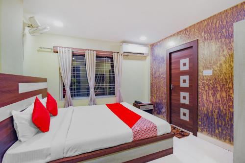 a bedroom with a bed with red pillows and a window at Hotel O Tranquil Stay in Kolkata