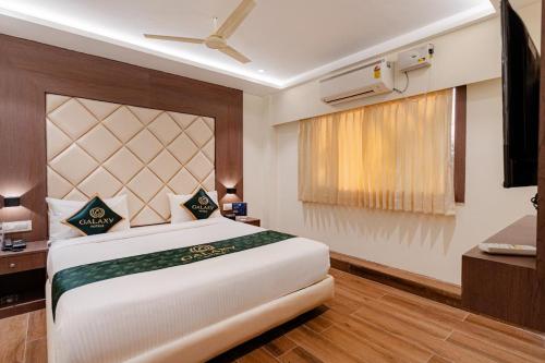 a bedroom with a bed and a flat screen tv at Galaxy Royal Suites in Bengaluru