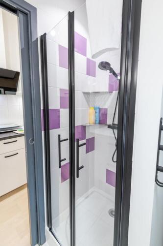 La salle de bains est pourvue d'une douche et de carrelage violet et blanc. dans l'établissement Au coeur de Newton, à Amboise