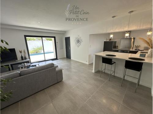 a living room with a couch and a kitchen at Un Petit Coin de Provence - Istres - Maison Contemporaine Avec Piscine Privée Chauffée, Entre Plages Et Provence, Borne 11 kW in Istres