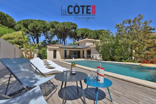 Un patio con dos mesas y una botella de vino. en Villa Marisol, en Carry-le-Rouet
