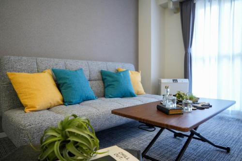 a living room with a couch with blue and yellow pillows at MP STYLE SAPPORO-37 in Minami-jūichijō