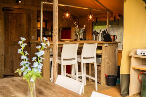une cuisine avec un bar et des tabourets blancs dans l'établissement Lodge Holidays - Glamping Fouesnant, à Fouesnant