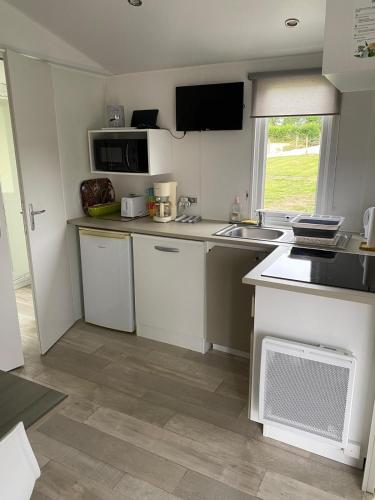 a kitchen with white cabinets and a sink and a window at Belle location face à l'étang in Landouzy-la-Cour