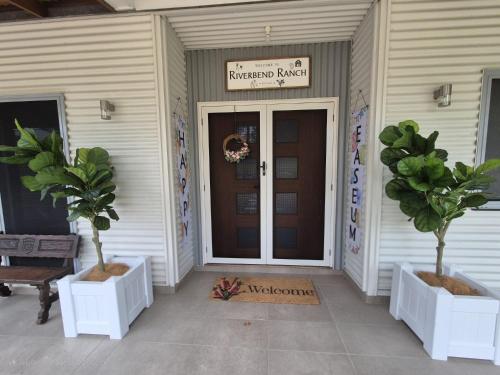 a front door of a house with two potted trees at Riverbend Ranch Tamborine in Tamborine