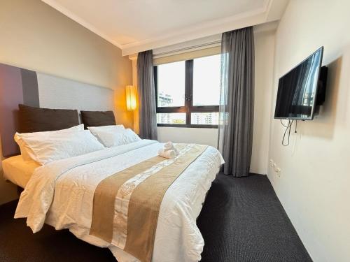 ein Schlafzimmer mit großem Bett und Fernseher in der Unterkunft Cozy 1 bedroom unit in parramatta Pool,Spa,Dining in Sydney