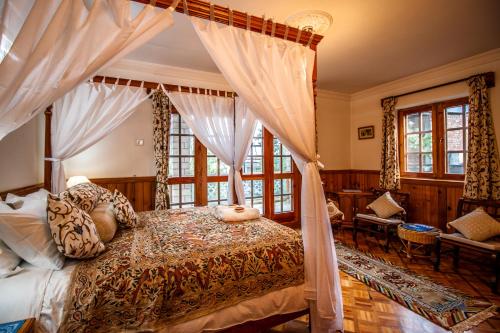 a bedroom with a canopy bed with curtains at Silverstone Mansions Cottages in Manāli