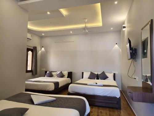 a room with two beds and a television in it at Lax Residency, White Town, Pondicherry in Puducherry
