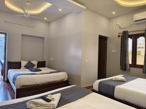 a hotel room with two beds and a window at Lax Residency, White Town, Pondicherry in Puducherry