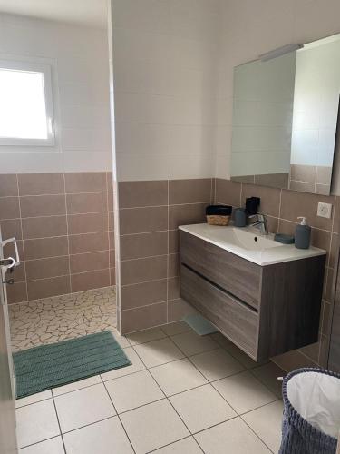 une salle de bain avec un lavabo et un miroir dans l'établissement Maison au calme à 900m du bourg, à Carcans